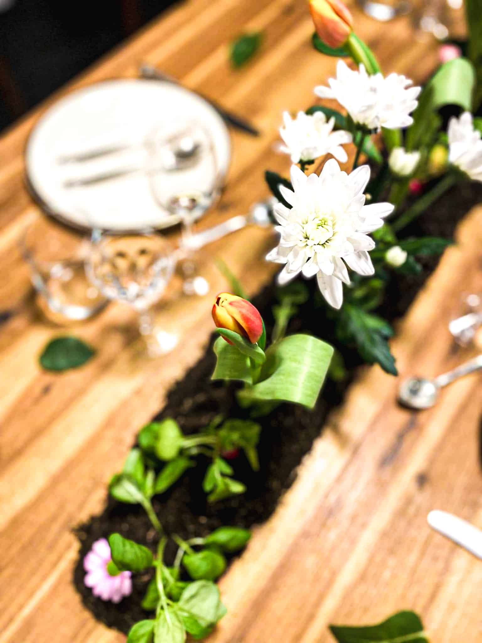 A set table with a bed of plants in the center.